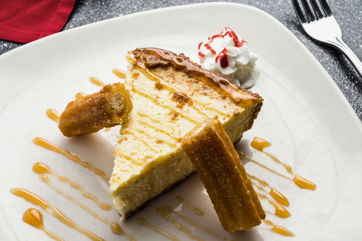 A slice of churro cheesecake with a cinnamon sugar crust and creamy filling.